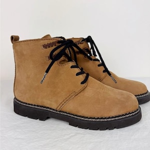 May include: A pair of brown leather lace-up boots with black laces and a black rubber sole.