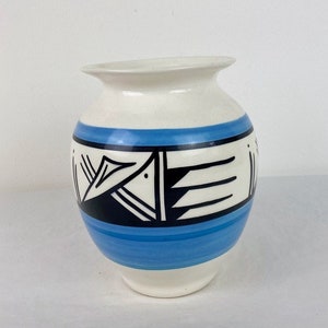 May include: White ceramic vase with a blue and black geometric design. The vase has a rounded body and a wide opening.