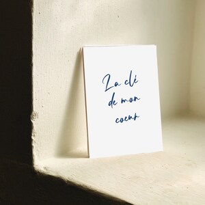 May include: A white card with blue cursive text that reads 'La clé de mon coeur'.