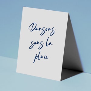 May include: A white card with the words 'Dansong song la pluie' written in blue cursive script.