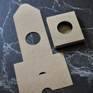 May include: A set of three brown cardboard boxes with round cutouts. The boxes are designed to be assembled into a tower shape.