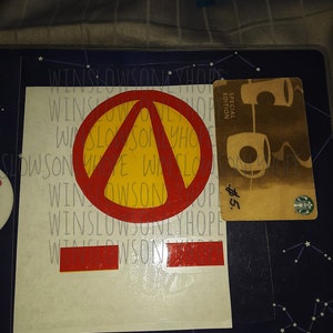 May include: A white sticker featuring a red and yellow geometric design, and a brown Starbucks gift card. The sticker has the text "WINSLOW ONLY HOPE" repeated. The gift card is a special edition.