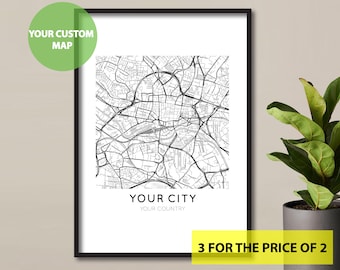 May include: A black and white city map print in a black frame. The map shows the streets of a city. The text below the map reads "Your City, Your Country". The text "3 for the price of 2" is in yellow at the bottom of the image.
