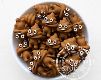 May include: A white bowl filled with numerous brown, cartoon-like poop emojis with smiling faces and white eyes. The emojis are in various poses, some standing and others lying down. The image is well-lit, with the emojis taking up most of the frame.