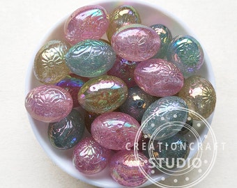 May include: A bowl of iridescent pastel Easter egg shaped beads. The beads are made of glass and have a glittery finish. The beads are in shades of pink, green, and gold.