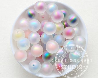 May include: A bowl of iridescent white glass beads with a frosted finish. The beads are various shades of pink, blue, and green.