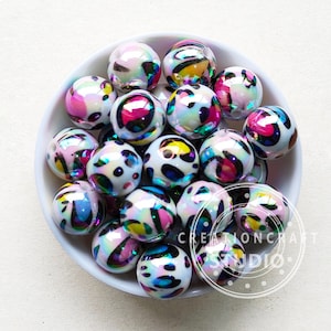 May include: A bowl of iridescent white beads with a black, pink, and yellow animal print design.