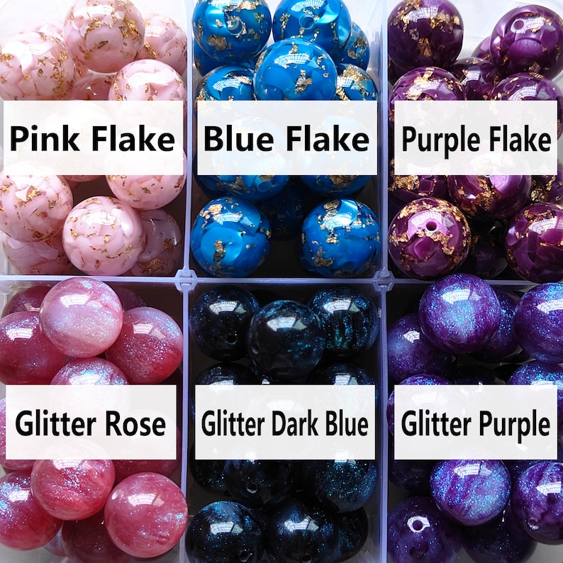 May include: Assortment of colourful glass beads with different finishes. Pink, blue, and purple beads with gold flakes. Glitter rose, glitter dark blue, and glitter purple beads.
