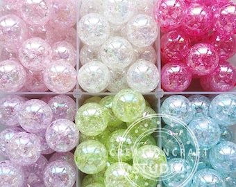 May include: Assortment of iridescent glass beads in six colors: pink, white, light green, light blue, lavender, and clear. The beads are arranged in six squares.