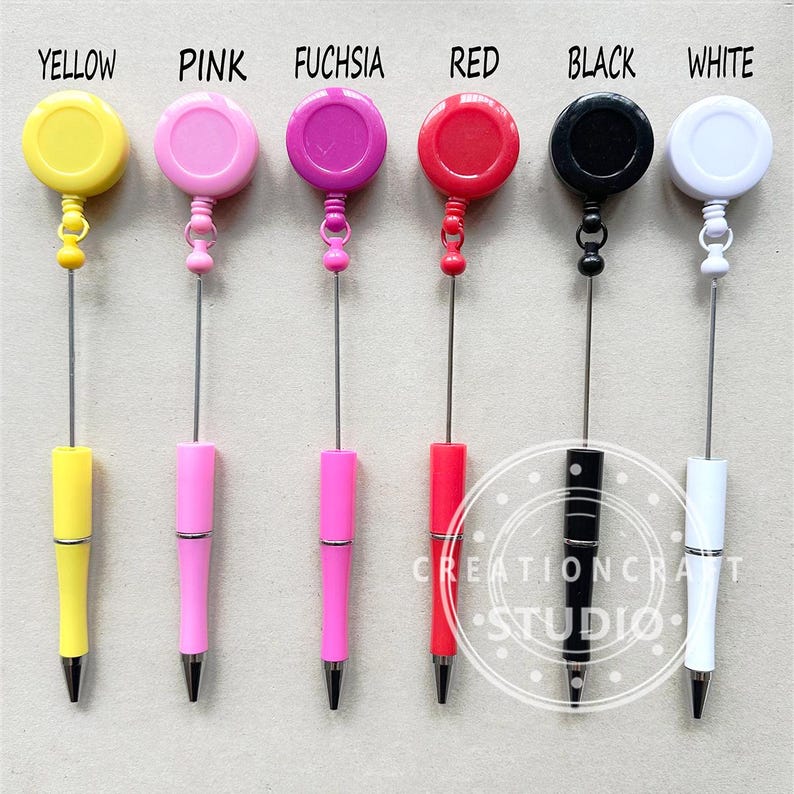 May include: Six retractable pens with different colored tops: yellow, pink, fuchsia, red, black, and white. The pens have a metal clip and a retractable tip.