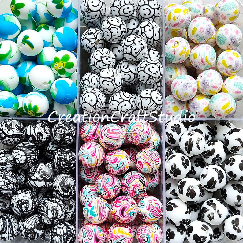 May include: Assortment of colourful silicone beads in various patterns, including smiley faces, swirls, paw prints, and floral designs. The beads are arranged in six clear plastic containers.