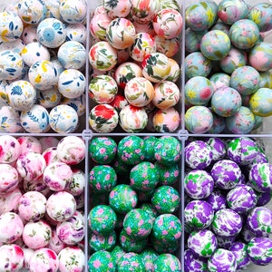 Pode incluir: Conjunto de contas de madeira coloridas com padrões florais e geométricos. As contas estão dispostas em seis filas, cada fila contém uma cor e um padrão diferente. As contas são perfeitas para artesanato, fabricação de joias e outros projetos criativos.