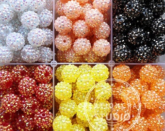 May include: Six containers of colourful iridescent round beads. The beads are arranged in rows of six. The colours are white, peach, black, red, yellow, and orange.