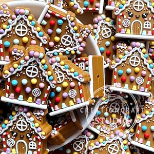 May include: A collection of brown gingerbread house charms featuring white icing details, colourful pastel candy accents, and a small lollipop graphic. Each charm has a smiling face with black eyes and a white door, arranged in a white bowl.