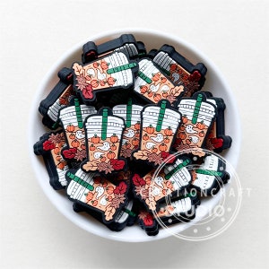 Peut inclure: Un bol rempli de plusieurs breloques en silicone noir, orange et blanc en forme de latte à la citrouille épicée avec une paille. Les breloques ont un thème d'automne avec des fantômes et des citrouilles.