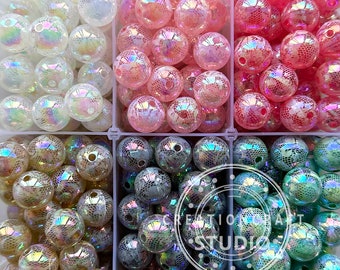 May include: Four containers of iridescent, round, plastic beads. The beads are in four colors: white, pink, light green, and brown. The beads have a textured, lace-like pattern.