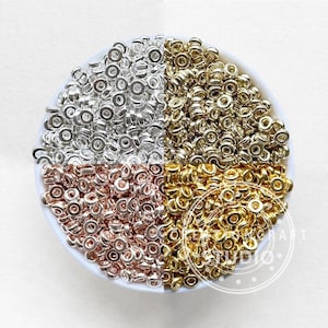 May include: A bowl filled with a variety of jump rings in silver, gold, and rose gold.