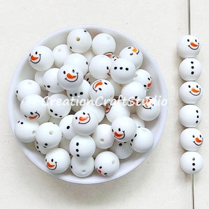 Peut inclure: Un bol de perles de bonhomme de neige en silicone blanc avec des visages peints orange et noir. Les perles mesurent 2 cm de diamètre et ont un trou au centre pour être enfilées.