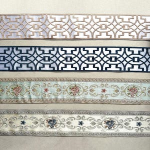 May include: Four different trims with intricate patterns. The top trim is white with a gold geometric design. The second trim is white with a black geometric design. The third trim is light blue with a floral design. The bottom trim is cream with a floral design.