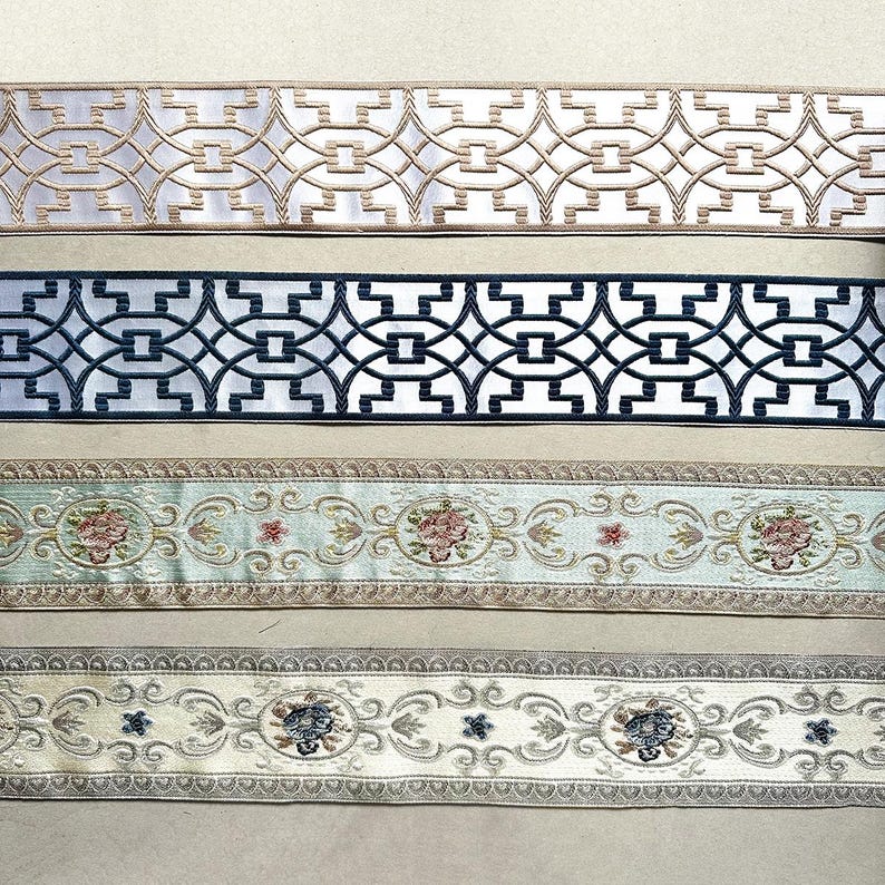 May include: Four different trims with intricate patterns. The top trim is white with a gold geometric design. The second trim is white with a black geometric design. The third trim is light blue with a floral design. The bottom trim is cream with a floral design.