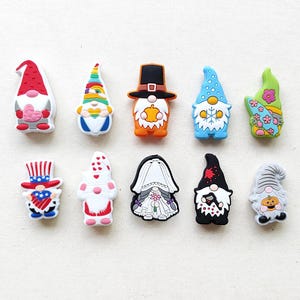 May include: Ten colorful gnome figurines with different designs and themes. The gnomes are made of plastic and have a variety of colors, including red, blue, green, white, and orange. The gnomes are all wearing hats and have beards.