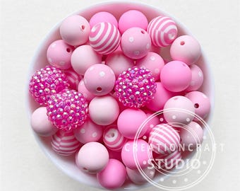 May include: A bowl filled with pink and white silicone beads. The beads have different patterns, including polka dots, stripes, and glitter.