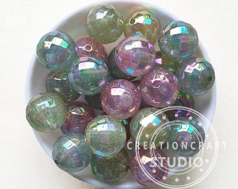 May include: A bowl of iridescent green and pink faceted glass beads. The beads are translucent and have a sparkly finish.