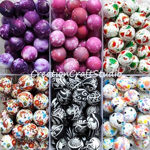 May include: Assortment of colourful, patterned, and textured round beads in six different designs. The beads are arranged in six separate compartments. The beads are made of polymer clay and are approximately 2.5 cm in diameter.