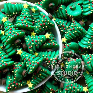 Puede incluir: Una colección de adornos verdes en forma de árbol de Navidad con estrellas amarillas, decoraciones de puntos rojos y amarillos y bases marrones. Los adornos están en un cuenco blanco y dispersos. Se incluye el texto "CREATION CRAFT STUDIO".