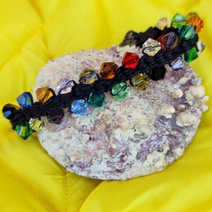 May include: A rainbow-coloured beaded bracelet with black string and a variety of crystal beads.