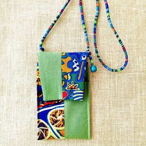 Peut inclure: Un sac à bandoulière en tissu patchwork vert et bleu avec un imprimé floral coloré. Le sac a une longue bandoulière et une petite poche sur le devant.