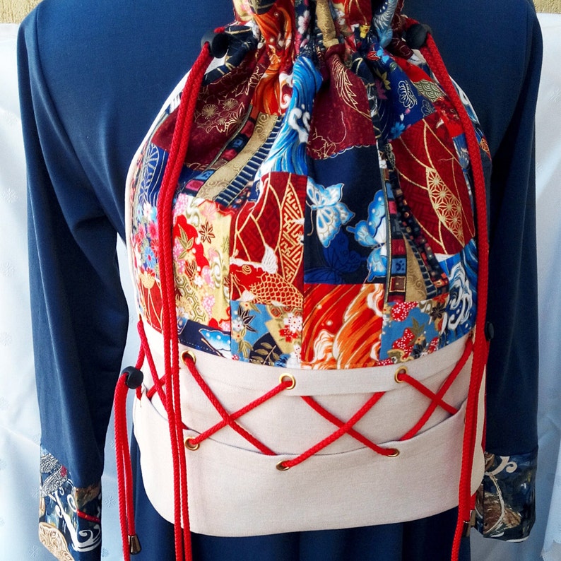 May include: A red, white and blue patchwork drawstring bag with a white canvas base and red laces. The bag is tied with a bow and has a decorative design.