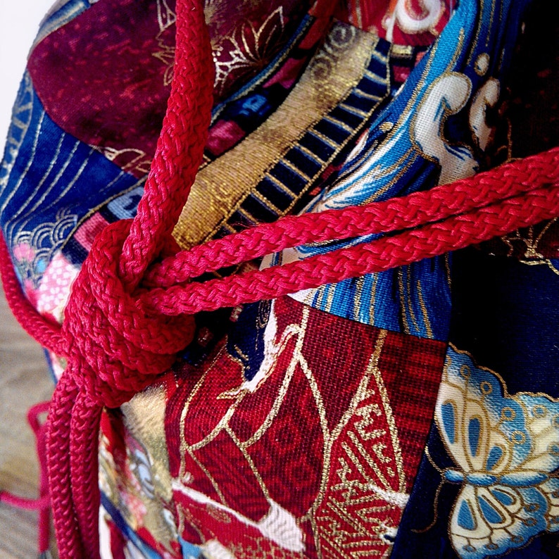 May include: A red fabric bag with a colourful floral pattern and a red rope tied around it.