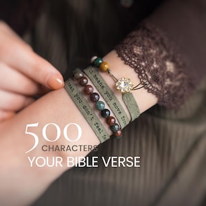 Könnte beinhalten: Ein Set aus drei geschichteten Armbändern mit olivgrünen Wildlederbändern mit schwarzem Text, mehrfarbigen runden Steinperlen und einem zentralen goldfarbenen runden Anhänger mit klaren Kristallen. Der Text lautet "even you don't feel far" und "means you move forward."