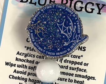 Puede incluir: Encanto de cerdo azul y blanco con un encanto de dragón azul y plateado con purpurina. El encanto del dragón tiene el texto "Un dragón sin su jinete es una tragedia. Un jinete sin su dragón está muerto." El encanto está unido a un cordón de cuentas azul y blanco. El fondo es una tarjeta azul y blanca con el texto "Blue Piggy" y "¡Gracias por tu pedido! Síguenos en TikTok, Instagram & Facebook."