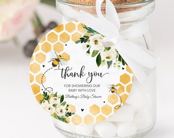 May include: A round, yellow and white thank you tag with a bee and honeycomb design. The tag says "Thank you for showering our baby with love" and "Brittany's Baby Shower".