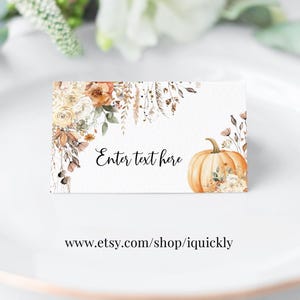 May include: A white place card with floral and pumpkin illustrations. The card features the text "Enter text here" in black script. The bottom of the card includes the website address www.etsy.com/shop/iquickly.