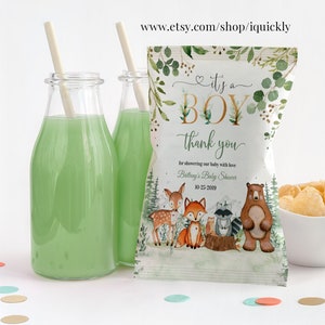 May include: It's a Boy baby shower favour bags with a woodland theme. The bags are decorated with a green and gold design and feature a deer, fox, raccoon, and bear. The text on the bag reads "It's a Boy" and "Thank you for showering our baby with love." The date of the baby shower is also included on the bag.