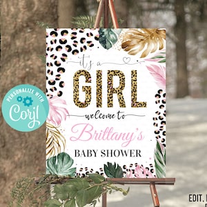 May include: Editable sign for a baby shower with a jungle theme. The sign features a pink and gold "It's a Girl" text with a leopard print background. The sign also includes tropical leaves and flowers. The text "Welcome to Brittany's Baby Shower" is at the bottom of the sign.