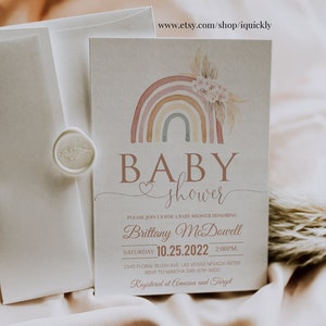 May include: A baby shower invitation with a watercolor rainbow design. The invitation features the text "BABY shower" and includes details for the event, including the date, time, and location. The invitation also includes the text "Registered at Amazon and Target".