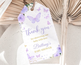 May include: Purple and gold thank you tag with butterflies and flowers. The tag says "Thank you for showering our baby with love, Brittany's Baby Shower".