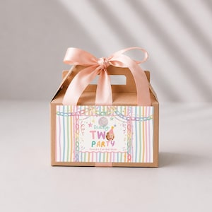 May include: A brown cardboard gable box with a light pink satin ribbon tied in a bow on top. The front features a label with pastel vertical stripes, a disco ball, and the text Ready TWO PARTY Olivia's 2nd Birthday with a photo of a child.