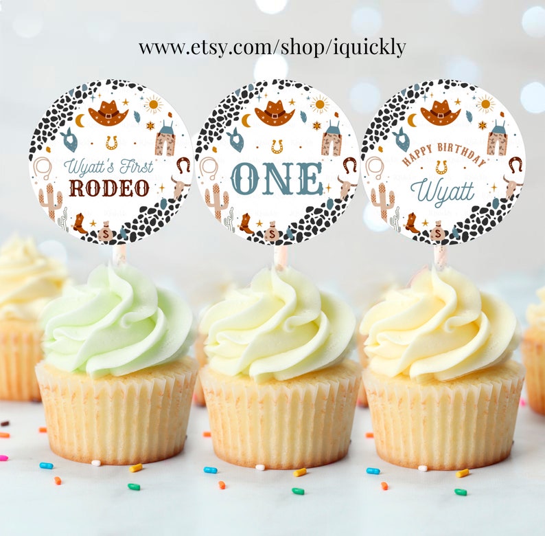 May include: Three round cupcake toppers with a cowboy theme. The toppers feature a white background with brown and black spots, a blue star, a yellow sun, a cactus, a horseshoe, a cowboy hat, and a pair of cowboy boots. The text on the toppers reads "Wyatt's First Rodeo", "One", and "Happy Birthday Wyatt".