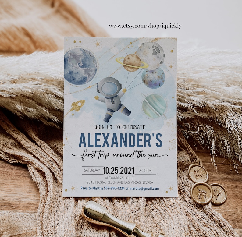 May include: A blue and white invitation with gold accents for a child's first trip around the sun party. The invitation features an astronaut holding balloons shaped like planets. The text on the invitation reads "Join us to celebrate Alexander's first trip around the sun. Saturday 10.25.2021 2:00PM. Alexander's House 2345 Floral Blush Ave Las Vegas Nevada. Rsvp to Martha 567-890-1234 or martha@gmail.com"