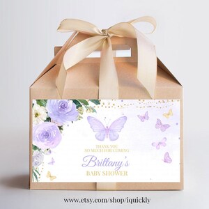 May include: A brown favor box with a purple and gold floral design and a butterfly. The box has a white label with the text "Thank you so much for coming Brittany's Baby Shower".