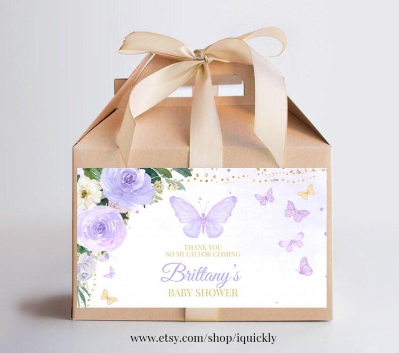May include: A brown favor box with a purple and gold floral design and a butterfly. The box has a white label with the text "Thank you so much for coming Brittany's Baby Shower".