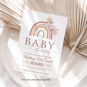 May include: A baby shower invitation with a watercolor rainbow design. The invitation features the text "BABY shower" and includes the date, time, and location of the event. The text "Registered at Amazon and Target" is also included.