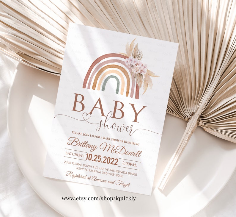 May include: A baby shower invitation with a watercolor rainbow design. The invitation features the text "BABY shower" and includes the date, time, and location of the event. The text "Registered at Amazon and Target" is also included.