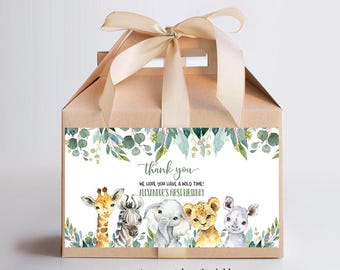 Op de afbeelding: Een bruine bedankbox met een groen en wit bedankkaartje. Het kaartje heeft een bladrand en illustraties van een giraffe, zebra, olifant, leeuw en neushoorn. De tekst op het kaartje luidt "Bedankt. We hopen dat je een wilde tijd hebt! Alexanders eerste verjaardag."