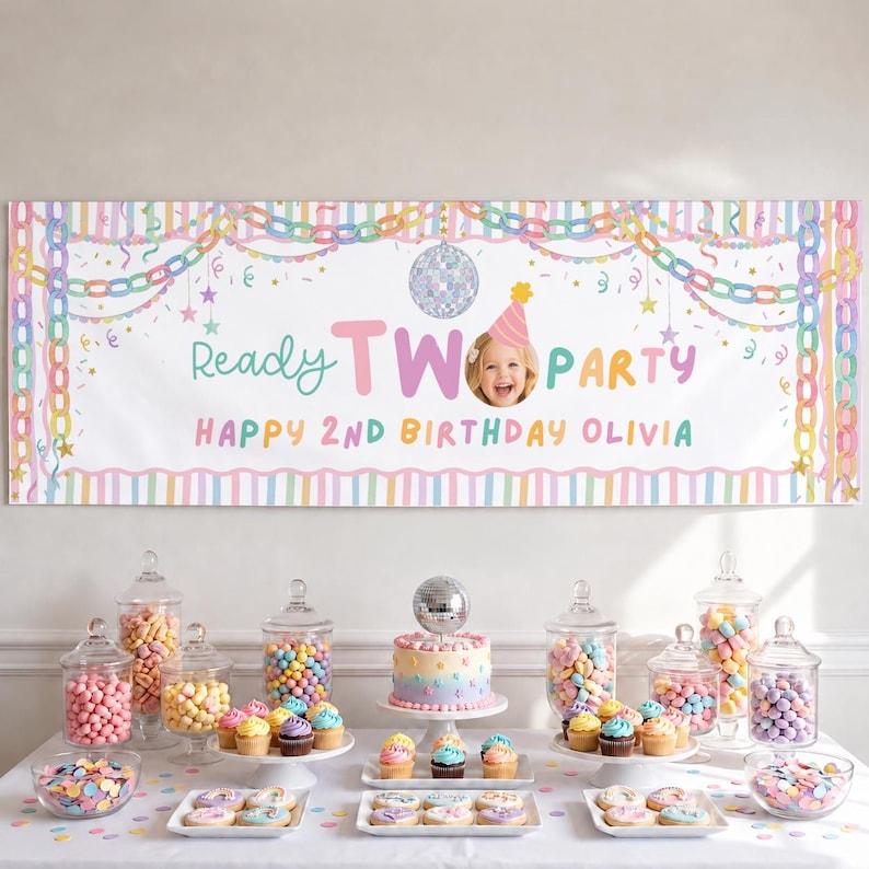 May include: A rectangular birthday banner featuring pastel stripes, a disco ball, and the text Ready TWO PARTY HAPPY 2ND BIRTHDAY OLIVIA with a photo of a child. Below, a table displays a tiered cake, glass jars of colorful candies, and cupcakes.